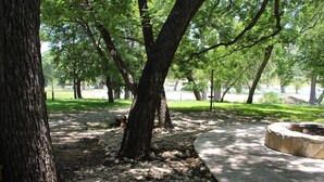 Un parque con árboles, un sendero de concreto y un hogar de piedra.