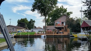 Enjoy waterfront views from the balcony of this two-story property, which features a dock and a small boat.