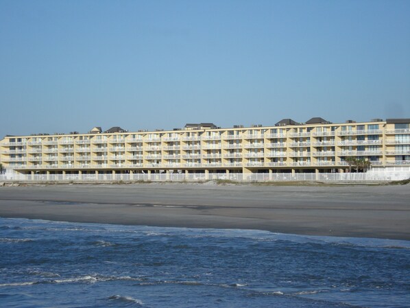 Un hôtel à plusieurs étages, doté de balcons, situé près d’une plage.