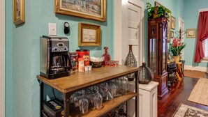 Une cuisine équipée d’une machine à café, d’une étagère avec des verres à vin et d’un meuble contenant des objets décoratifs.