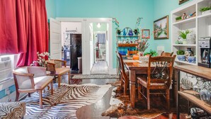 Un coin repas avec un tapis à motifs zébrés, des chaises en bois, une table et un rideau rouge.