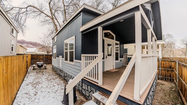 A two-story house with a front porch, a stone foundation, and a wooden deck.