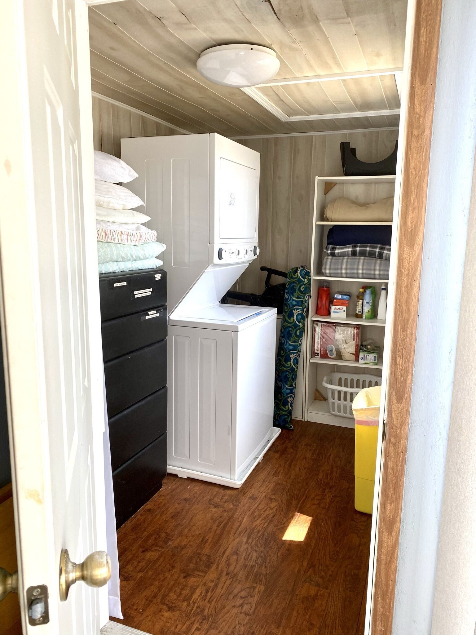 A laundry room with a washing machine, a dryer, and shelves with folded clothes and laundry supplies.
