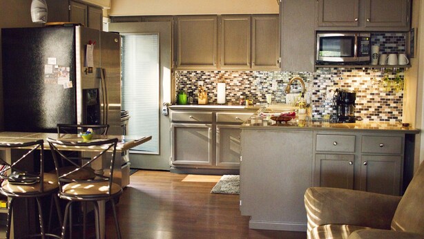 Una cocina moderna con una isla central, taburetes de bar y una mesa de comedor.