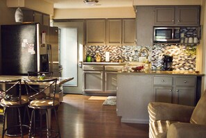 A modern kitchen with a central island, bar stools, and a dining table. - Come and play at Escape 2 the Lake! (Gravois Mills)