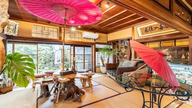 Un intérieur japonais traditionnel avec un sol recouvert de tatamis, des meubles en bois et de grandes fenêtres.