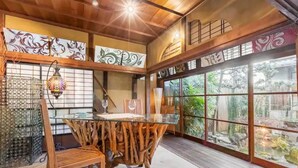 Une pièce de style japonais traditionnel, avec un sol recouvert de tatamis, une petite table en bois et une cloison en verre donnant sur un jardin.