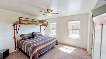 Une chambre avec un lit superposé, un ventilateur de plafond et une vue sur l’extérieur par une fenêtre.