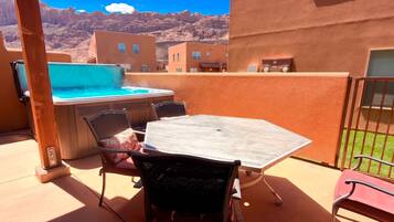 Une terrasse extérieure avec un jacuzzi, une table et des chaises.