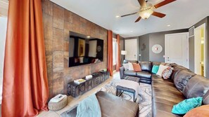 A modern living room with a sectional sofa, a flat-screen TV mounted on the wall, and a ceiling fan. - Entrada at Moab - 430, Brand New 4 Bedroom Luxury T (Moab)