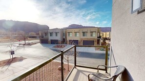 A balcony with a metal railing, a chair, and a view of a building complex with multiple garages. - Entrada at Moab - 430, Brand New 4 Bedroom Luxury T (Moab)