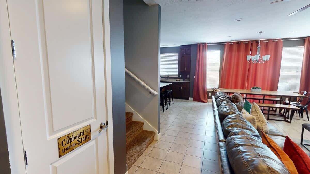 A hotel room with a staircase leading to a dining area, a sofa, and a sign on the door.