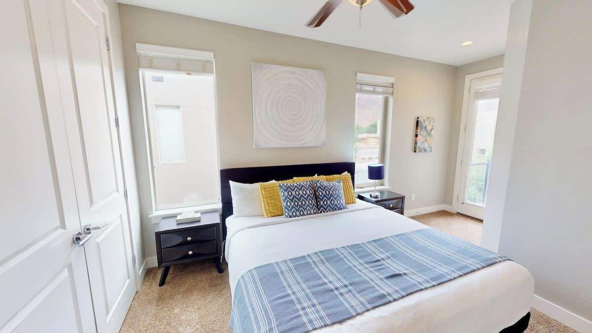 A bedroom with a bed, bedside tables, a ceiling fan, and a window.