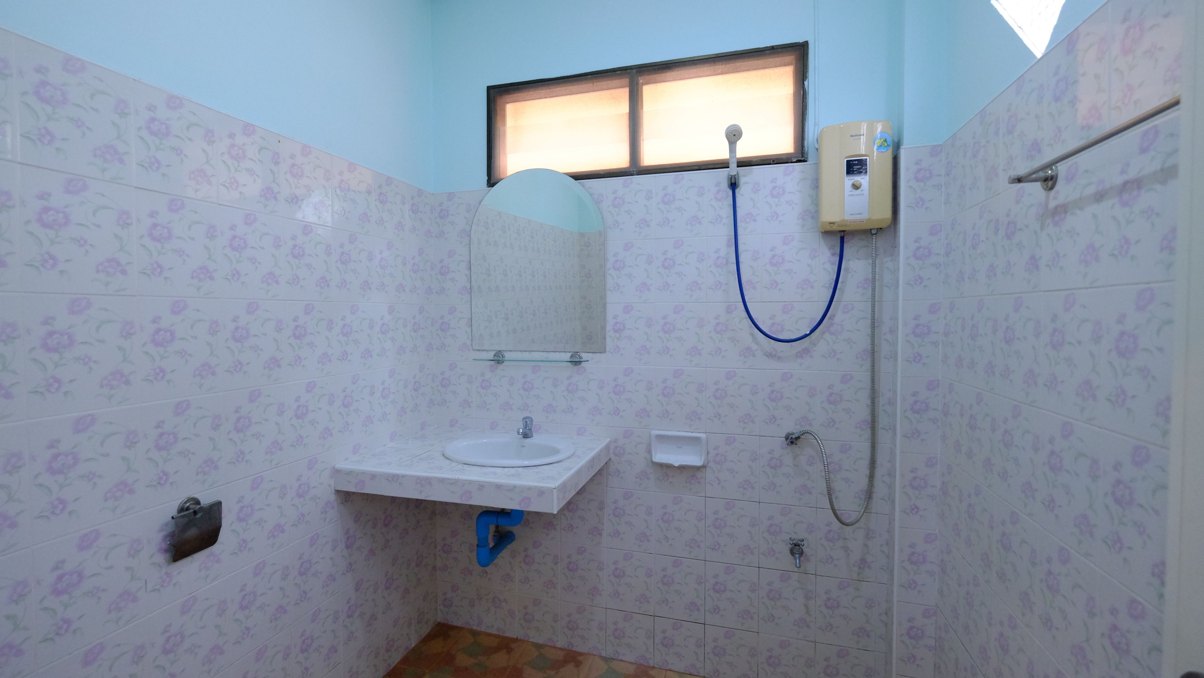 Casa de banho com lavatório, espelho, chuveiro e janela.