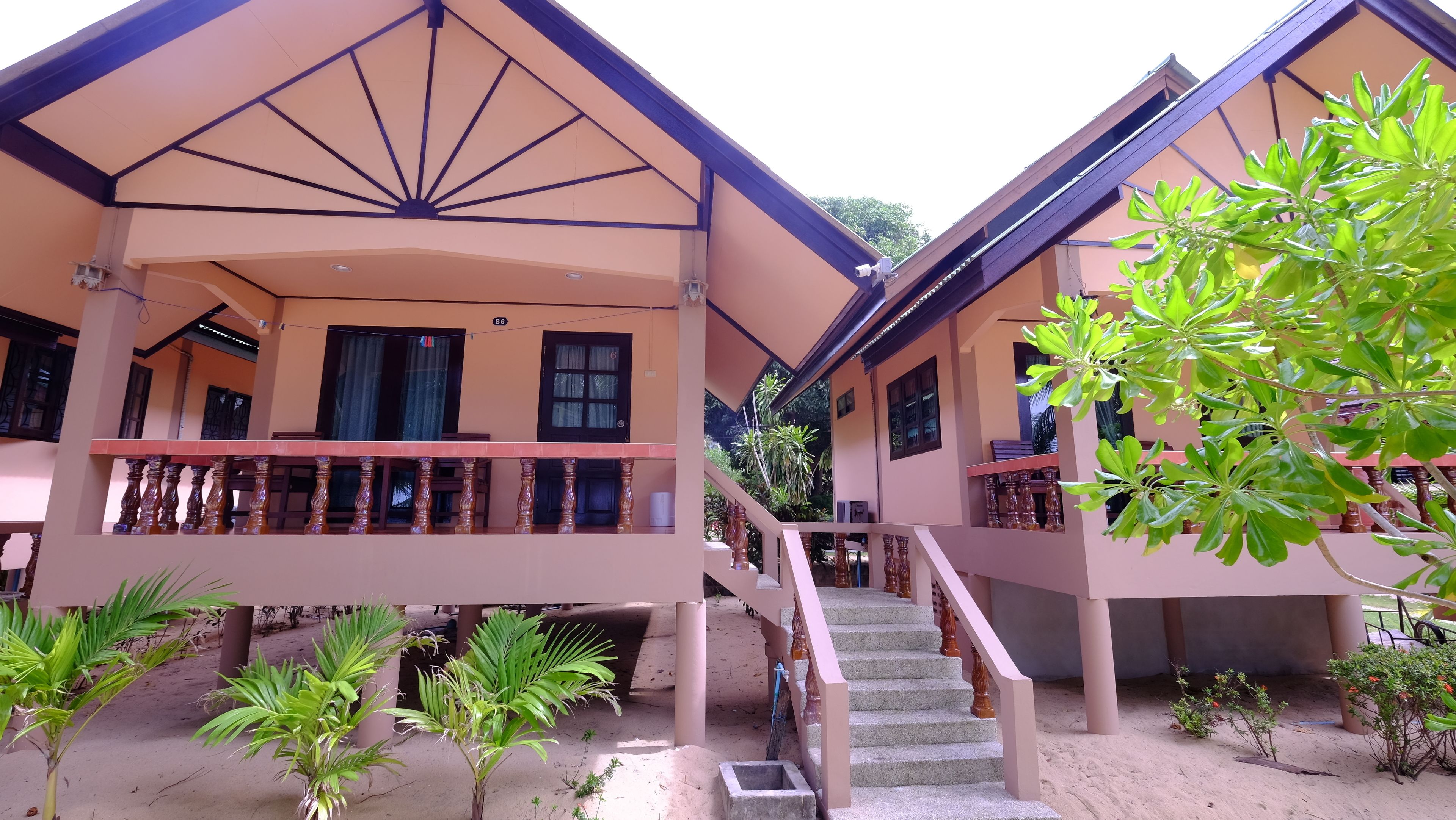 A two-story building with a balcony, a staircase, and a garden area.