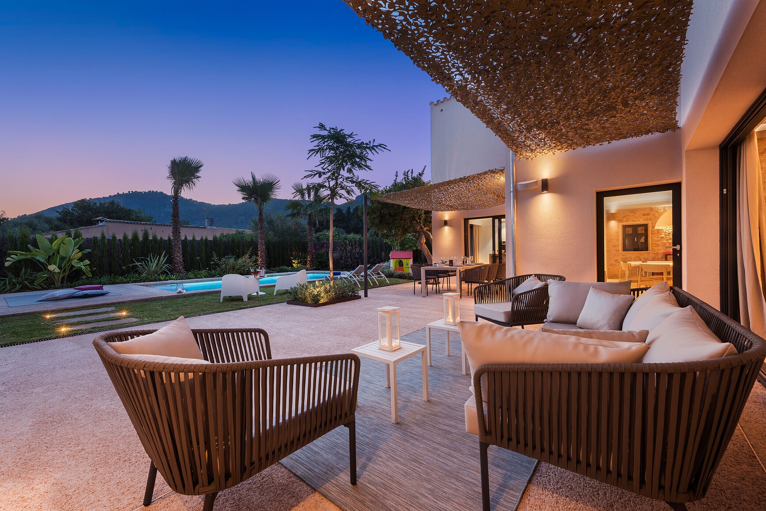 Un espace patio aménagé avec des meubles en osier, une piscine et une vue sur les montagnes.