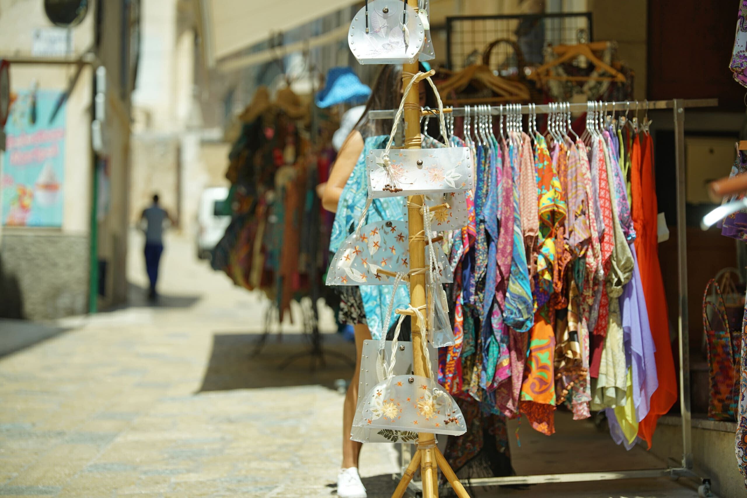 A street market with colorful clothing and accessories on display.