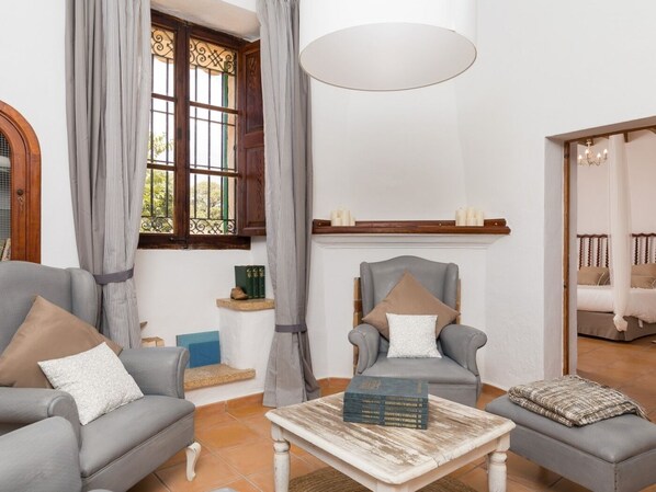 Una sala de estar con dos sofás grises, una mesa de centro, una chimenea y una ventana con cortinas.