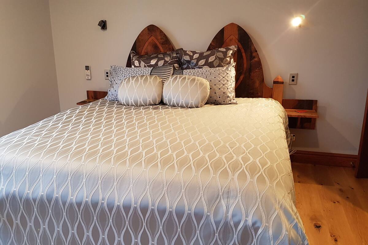 A neatly made bed with a patterned bedspread, a wooden headboard, and a bedside table with a lamp.