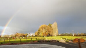 A rural landscape with a rainbow, a fenced pasture, and a house in the background. - BRUNTWOODLODGE - Adults Only (Tamahere)