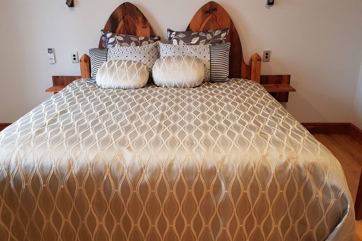 A bed with a patterned bedspread and multiple pillows.