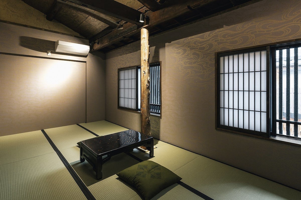 Um quarto japonês tradicional com tatames, uma mesa baixa e biombos shoji.