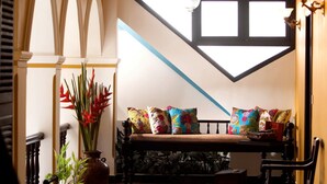 A cozy seating area with a bench, a potted plant, and a patterned floor. - Waterfront Granary A Museum Hotel (Kochi)