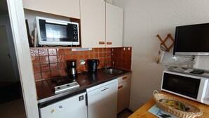 A compact kitchen with a microwave, coffee maker, and dishwasher.