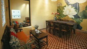 A dining area with a checkered floor, a wooden table, chairs, a vase with flowers, and a large wall mural.