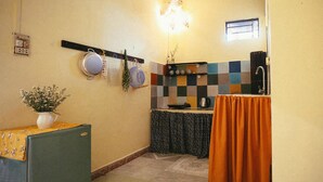A compact kitchen with a refrigerator, a sink, and a tiled backsplash.
