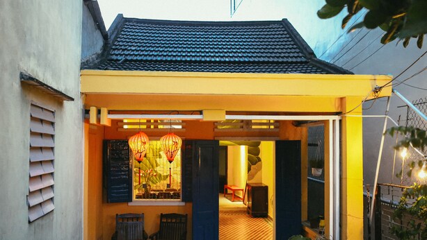 A traditional house with a tiled roof, a checkered floor, and a small porch area with chairs.