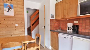 Une cuisine avec des meubles de rangement en bois, un lave-vaisselle et une machine à café.