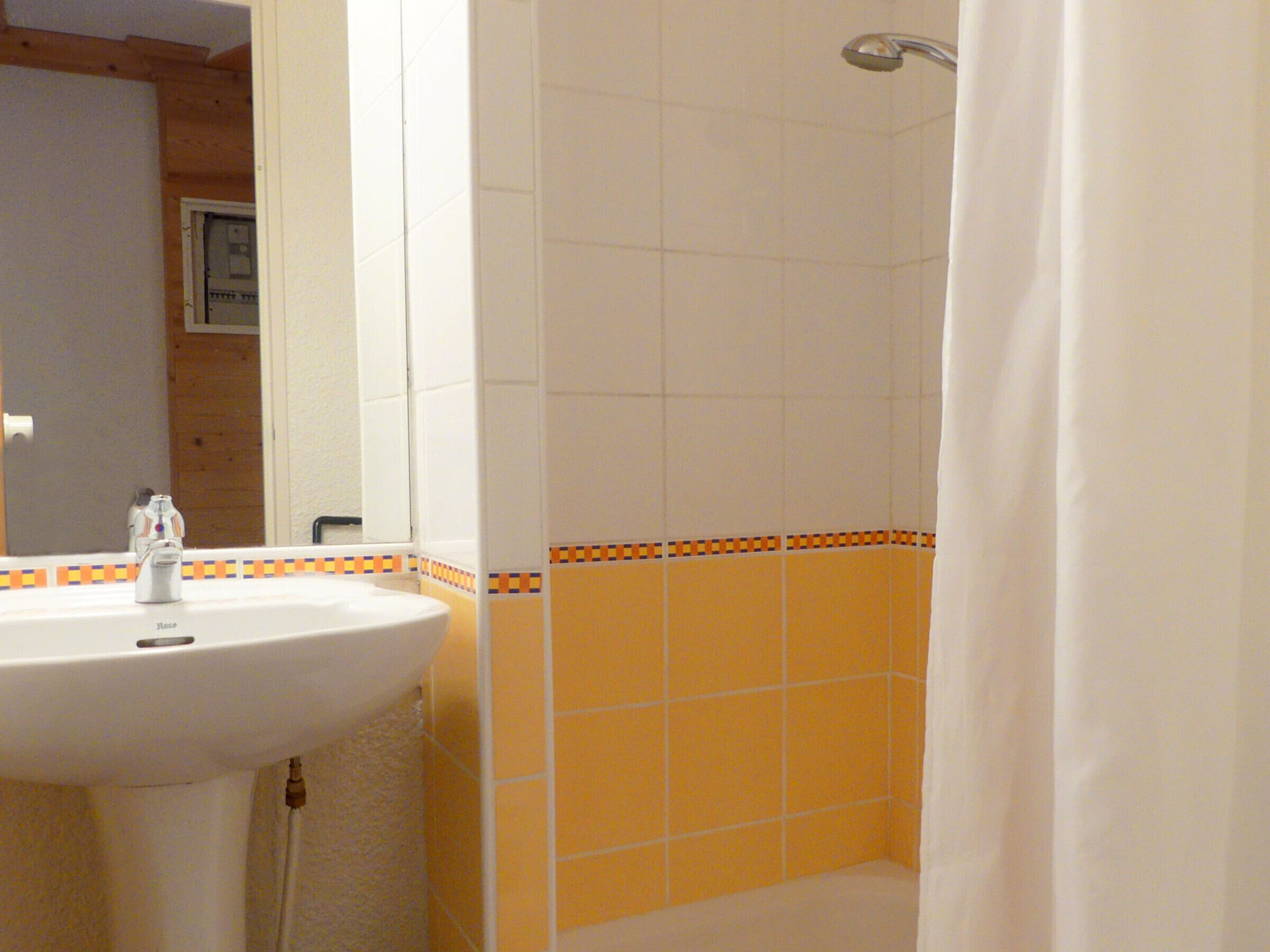 Une salle de bain avec un lavabo, une douche et des murs carrelés.