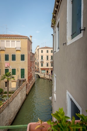 A narrow canal flanked by historic buildings with balconies and a bridge. - Angeles Inn (Venice)