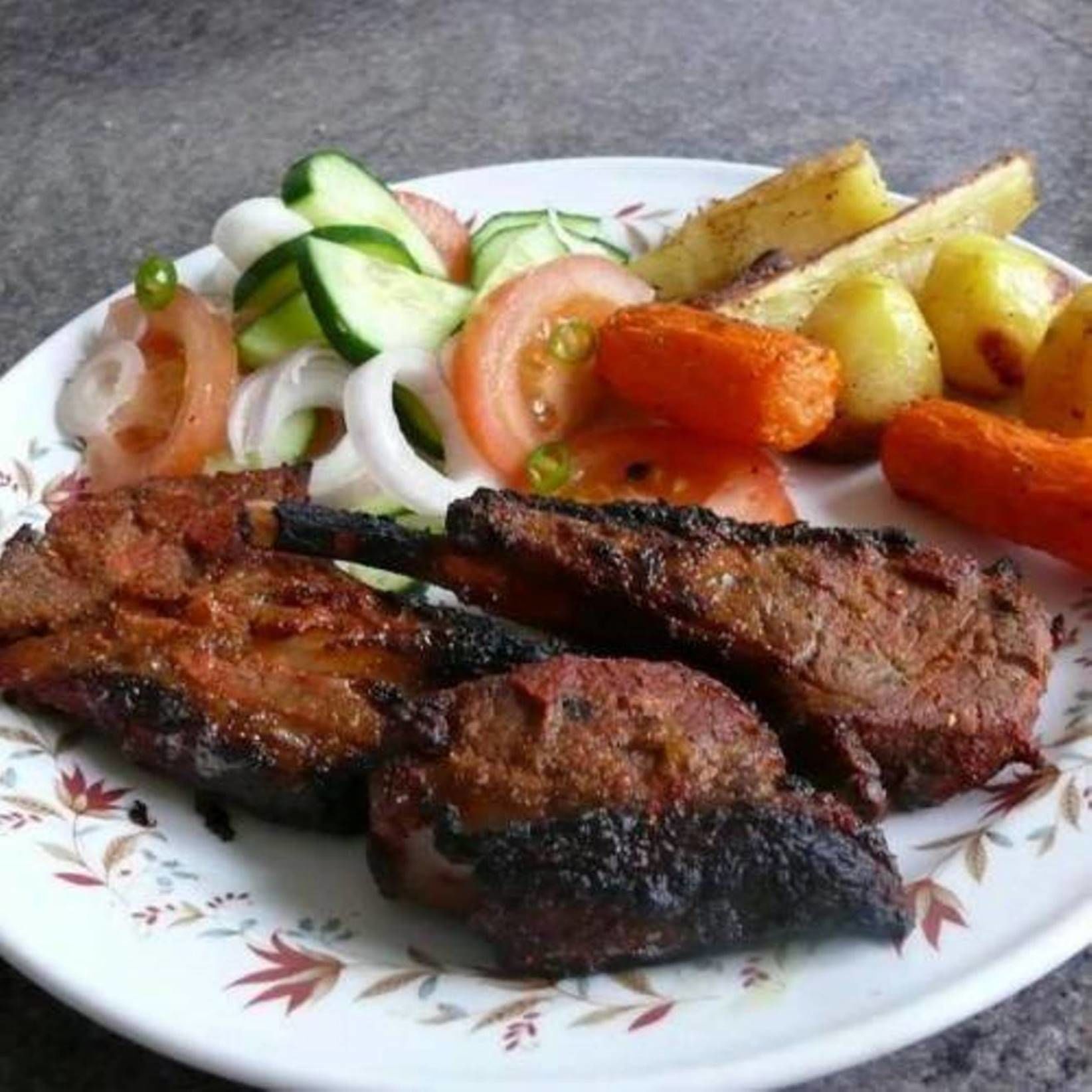 A plate with grilled meat, vegetables, and potatoes.