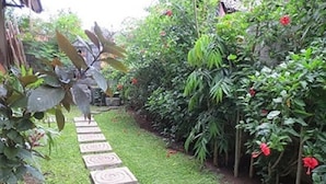A garden pathway with a spiral pattern on the ground, surrounded by lush greenery and flowering plants. - Bali Sari Homestay (Karangasem)