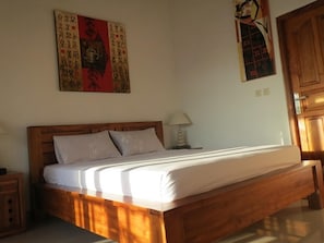 Ein hölzernes Bett mit einer weißen Matratze in einem Raum, der ein Holz-Kopfteil hat.