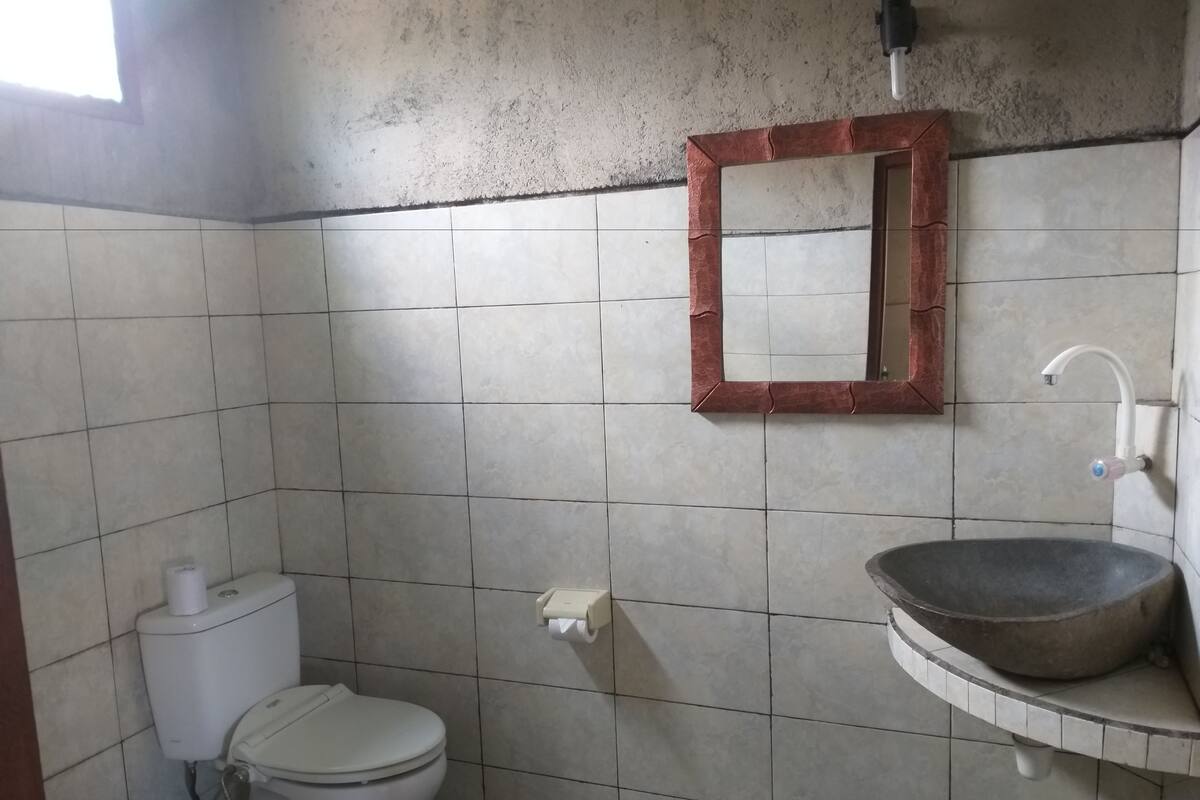 A small bathroom with a toilet, a sink, and a mirror.