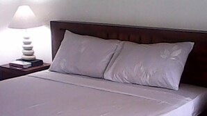 A neatly made bed with a wooden frame and white bedding. - Bali Sari Homestay (Karangasem)