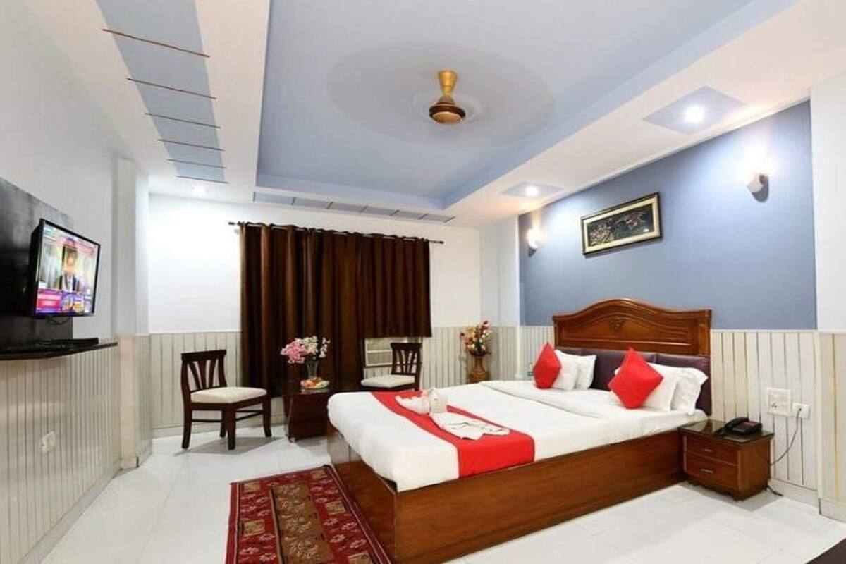 A hotel room with a bed, a TV, a desk, and a chair.