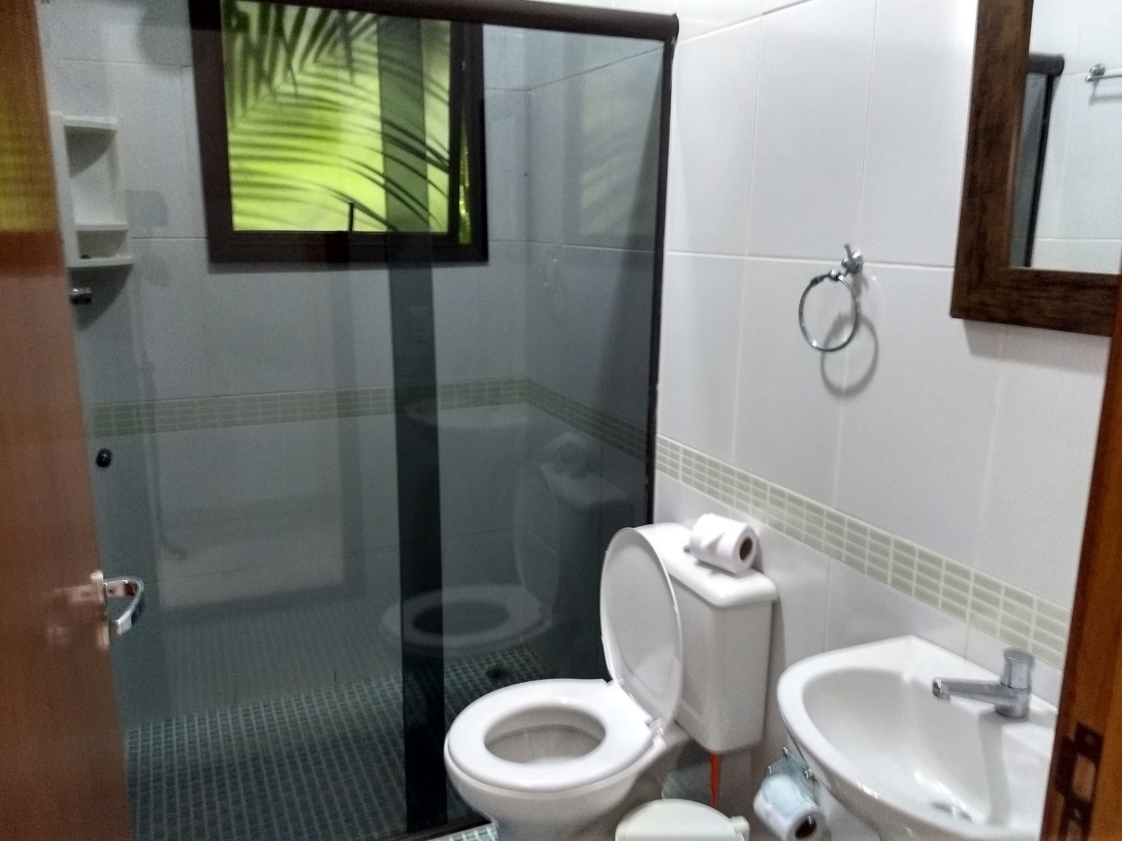 Un baño con cabina de ducha de vidrio, inodoro y lavamanos.