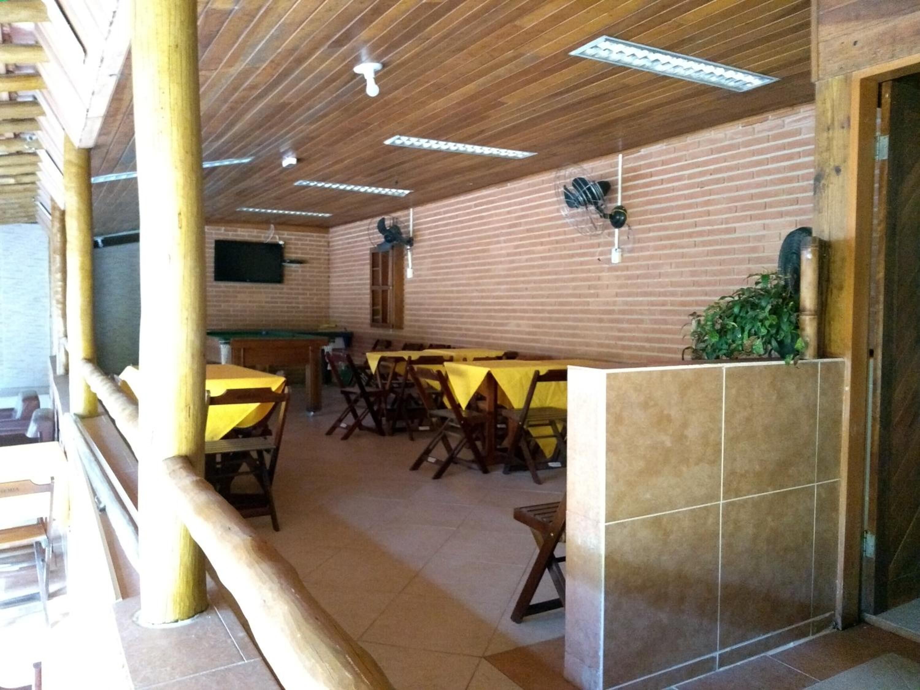 Comedor con mesas y sillas de madera, una mesa de billar y una pared de ladrillo.