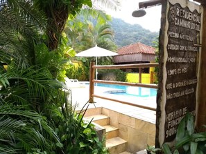 A pool area with steps leading to a building, surrounded by lush greenery. - Rc Sol de Boiçucanga Suites (São Sebastião)