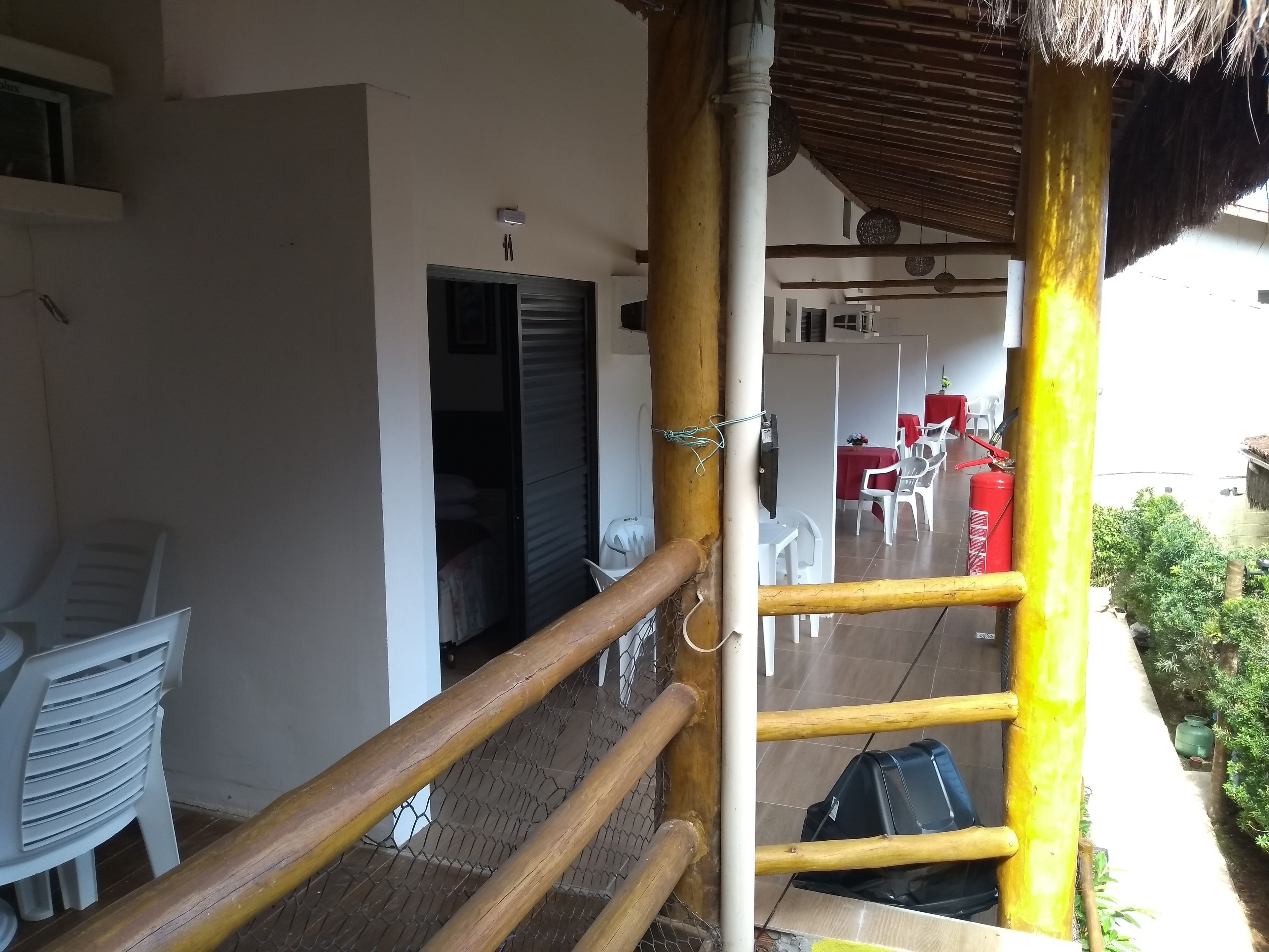 A staircase with a wooden handrail leading to a covered outdoor area with tables and chairs.