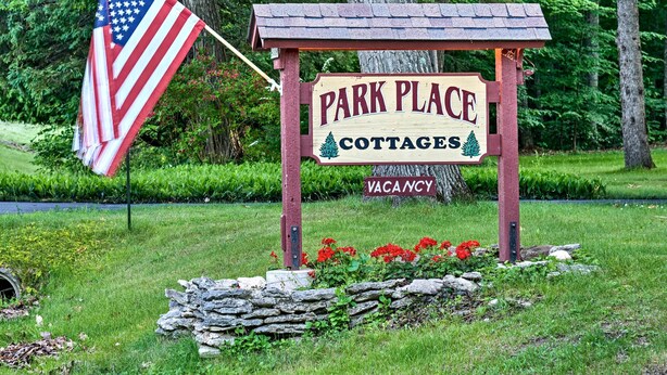 Señal de madera con la inscripción 'Park Place Cottages' y 'Disponibilidad', indicando cabañas disponibles.