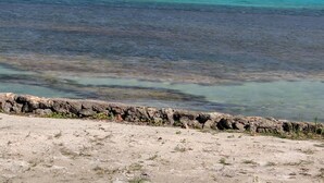 Paisatge costaner amb aigües turqueses cristal·lines, un litoral rocos i vegetació escassa.