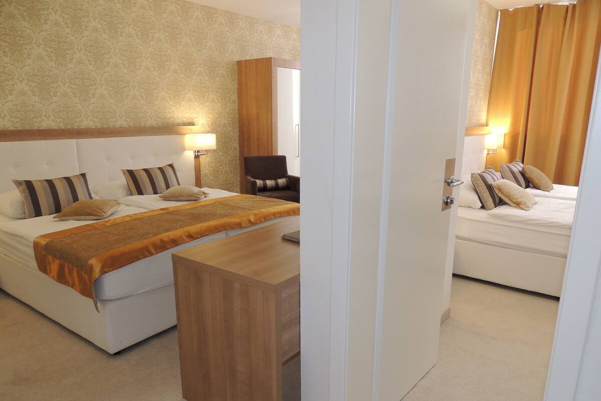 A hotel room with a bed, a chair, a desk, and a nightstand.