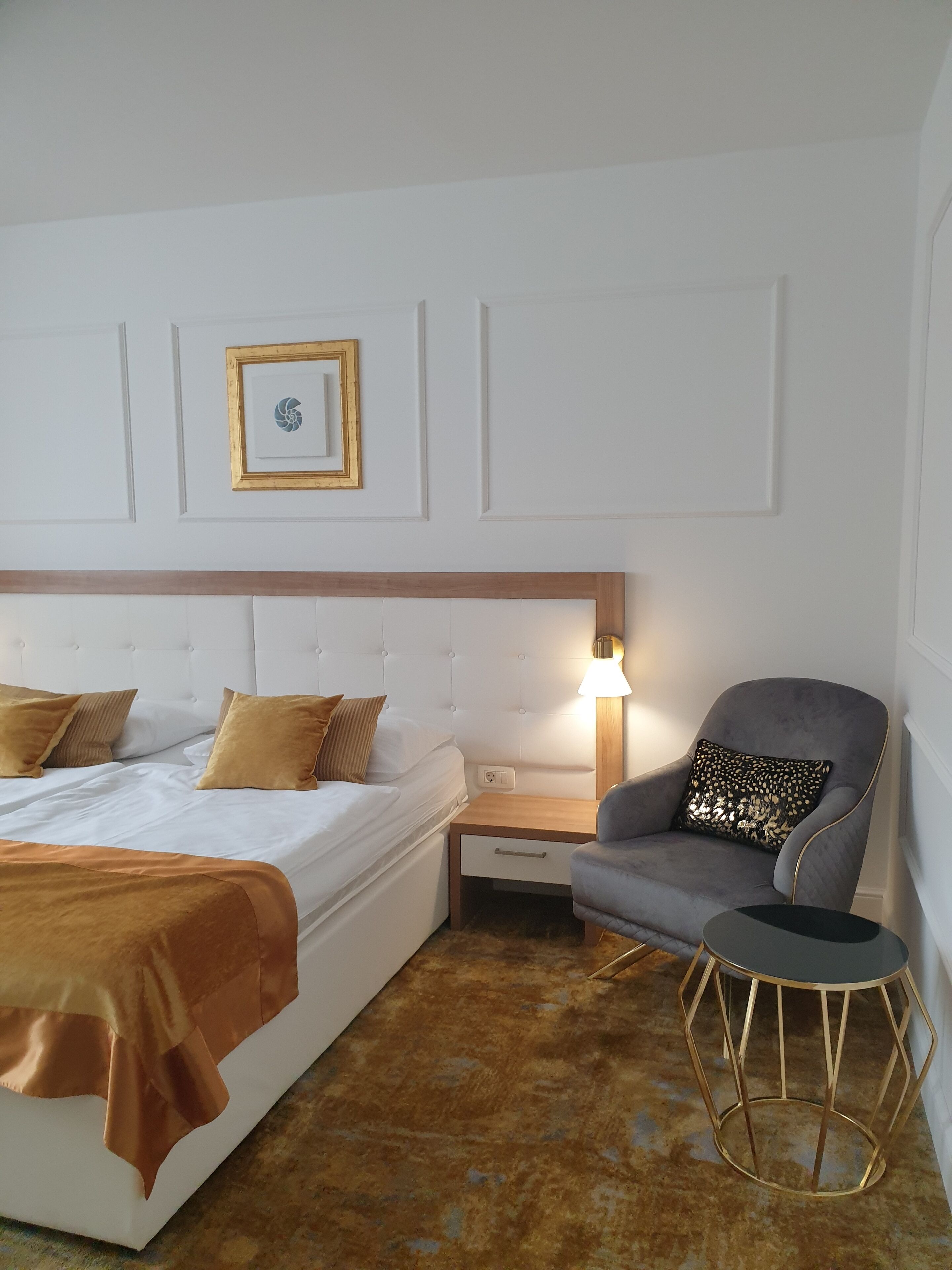 A bedroom with a bed, a nightstand, a chair, and a lamp.