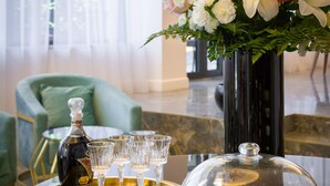 A table with a bottle, glasses, and a floral arrangement. - Hotel Corner (Split)