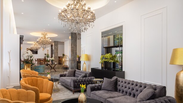 A spacious living room with plush sofas, a chandelier, and a dining area in the background. - Hotel Corner (Split)